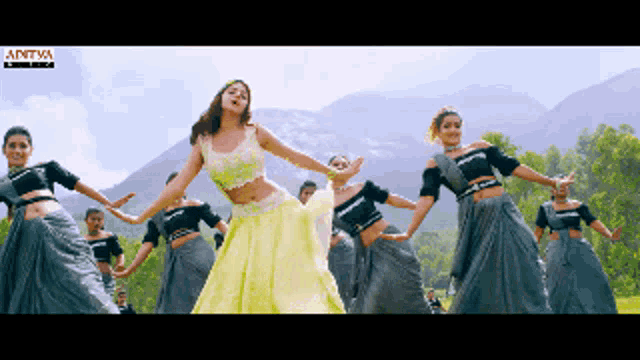 a woman in a yellow dress is dancing in front of a group of dancers