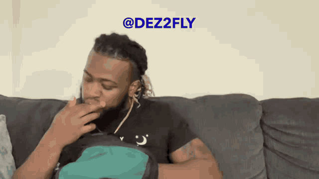 a man is sitting on a couch with a green backpack and the words @dez2fly on the bottom