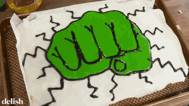 a cake with a green fist on it and the word delish on the bottom