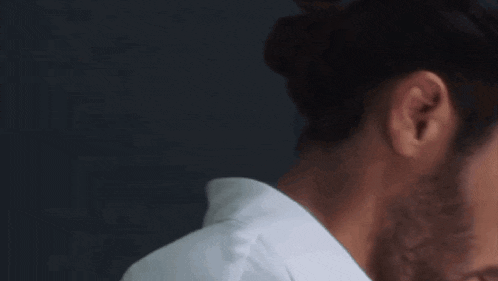 a close up of a man 's face with his eyes closed and a bun in his hair .
