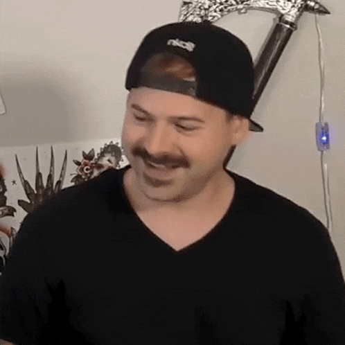 a man with a mustache is wearing a hat and a black shirt .