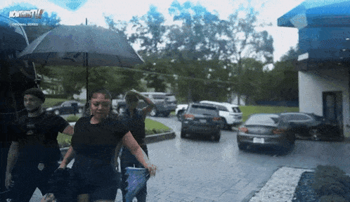 a woman holding an umbrella walks down a street in the rain while a man holds her hand