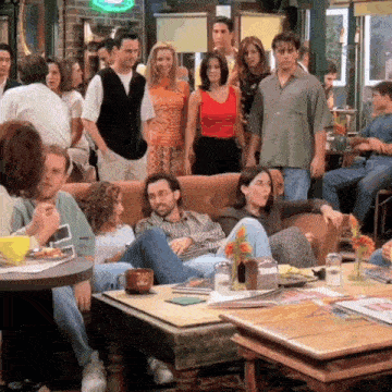 a group of people are gathered around a couch in a cafe