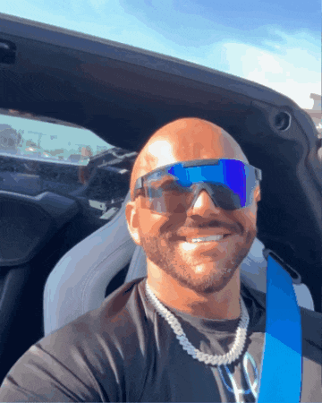 a man wearing sunglasses and a honda logo on his shirt smiles