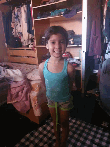 a little girl wearing a blue tank top and shorts