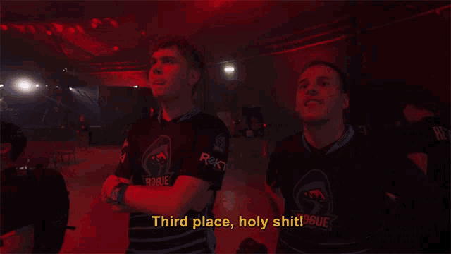 a man in a rogue shirt says " third place holy shit " in a dark room