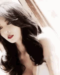 a woman with long black hair and red lipstick is wearing a white dress .