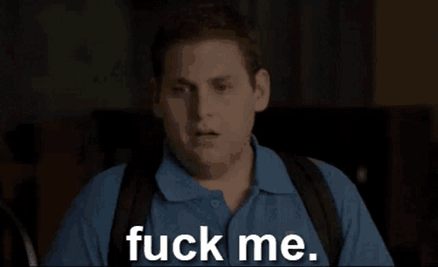 a man in a blue shirt is saying `` fuck me '' while holding a backpack .