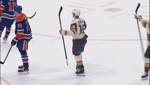 a hockey player with the number 16 on his helmet is giving another player a high five