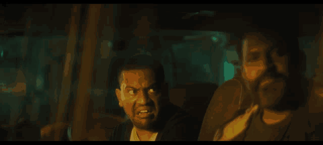 a man with a beard is sitting in the back seat of a car with another man