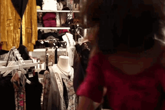 a woman in a red shirt is looking at clothes on display in a store