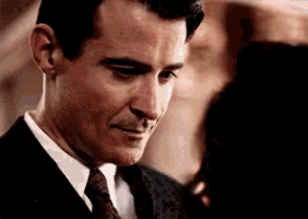 a man in a suit and tie is smiling and looking down .