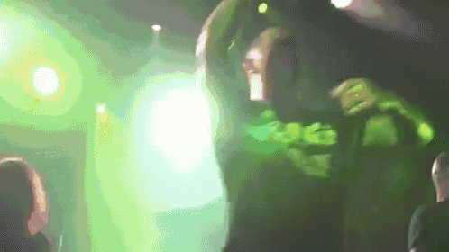 a man in a green shirt with the number 96 on it is dancing on a stage
