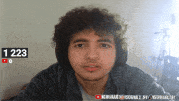 a man with curly hair is looking at the camera with the number 1223 behind him