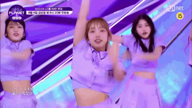 a group of girls are dancing on a stage while wearing purple clothes .