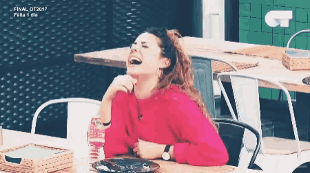 a woman in a red sweater is laughing while sitting at a table in front of a ct logo