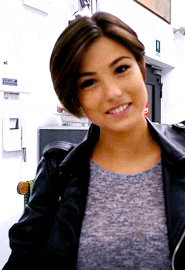 a woman wearing a grey shirt and a black jacket smiles