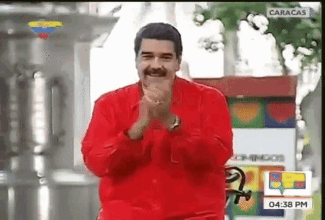 a man in a red shirt is clapping on a television screen
