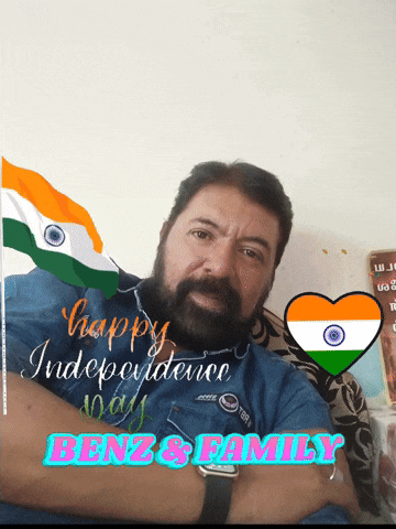 a man with a beard is sitting in front of a sign that says happy independence day benz and family