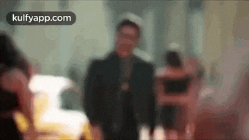 a blurry picture of a man standing in front of a crowd of people .