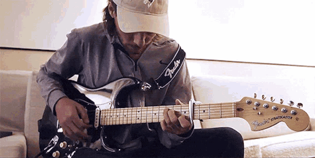 a man playing a guitar with a strap that says fender