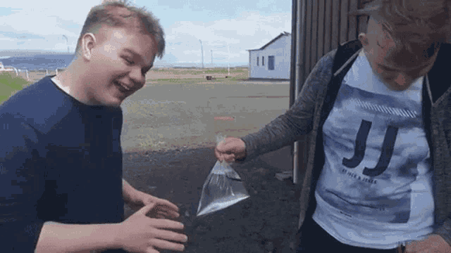 a man wearing a jj t-shirt holds a plastic bag
