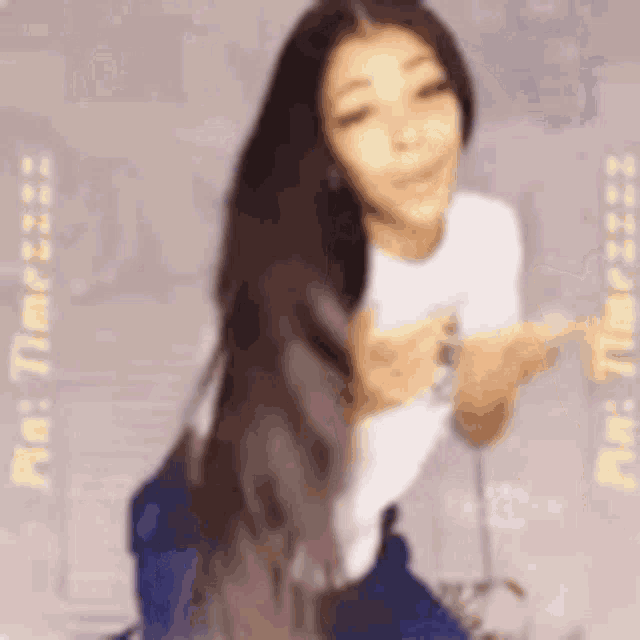 a woman in a white shirt and blue jeans is kneeling down and giving a thumbs up .