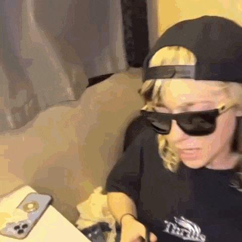 a young girl wearing sunglasses and a hat is sitting on a couch .