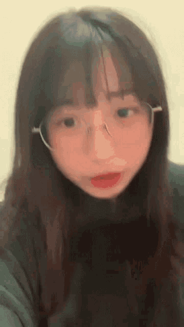 a girl wearing glasses and a green turtleneck is looking at the camera