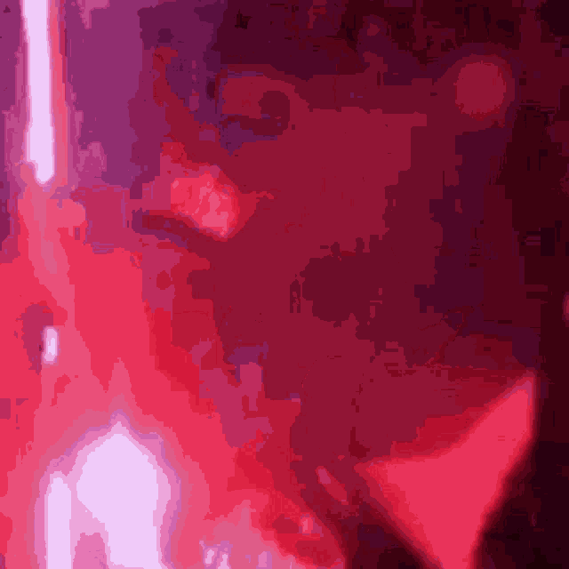 a close up of a person 's face in a dark room with red lights behind them .
