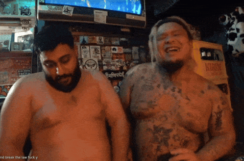 two shirtless men are laughing in front of a crate that says kirin on it