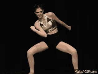 a woman in a crop top and black shorts is dancing on a make a gif.com website