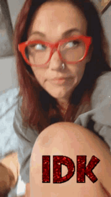 a woman with red glasses and the word idk on her knee