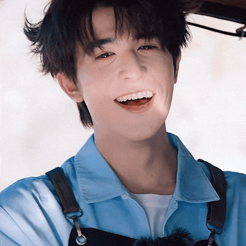 a young man wearing a blue shirt and an apron smiles