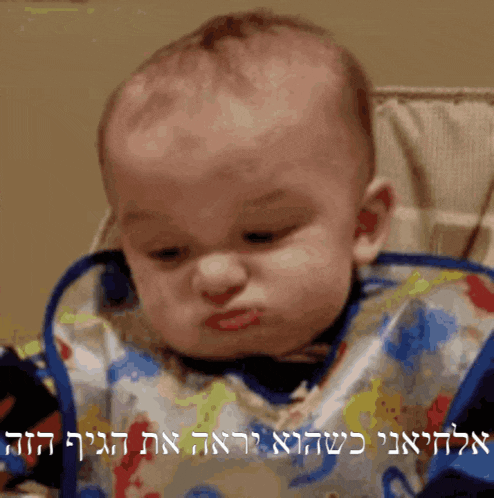 a baby is wearing a bib and making a funny face in a high chair