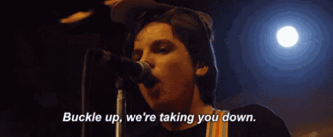 a man is singing into a microphone and saying buckle up we 're taking you down