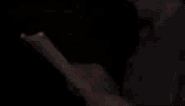 a man is holding a piece of paper with a light on it in the dark .