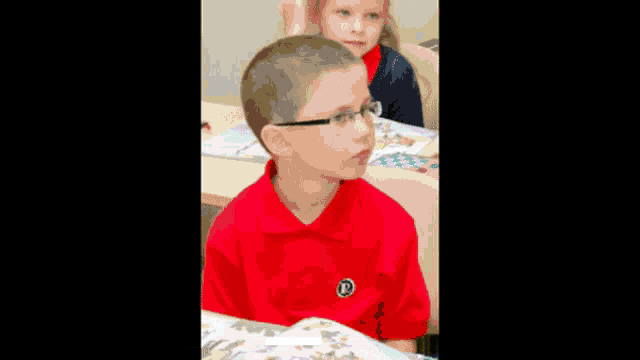 a boy in a red shirt sits in a classroom next to a sign that says " karmas moment "