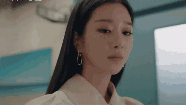 a close up of a woman wearing earrings and a white jacket