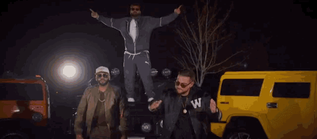 three men are posing for a picture with one wearing a jacket that says w on it