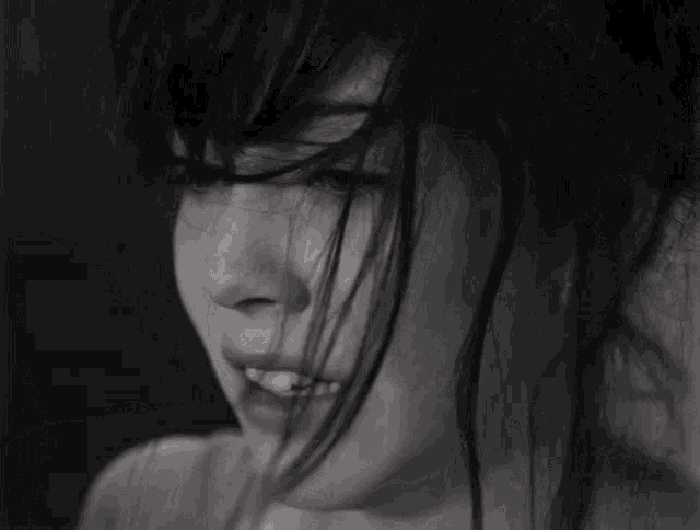 a black and white photo of a woman 's face with her hair blowing in the wind