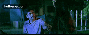 a man and a woman are standing next to each other in the dark .
