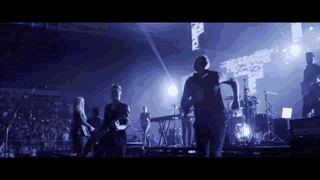 a group of people are dancing on a stage in front of a huge crowd