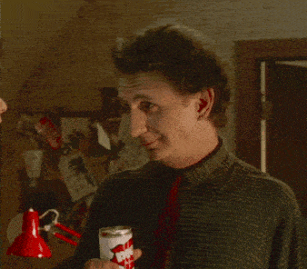 a man in a green shirt and red tie holds a can of diet coke