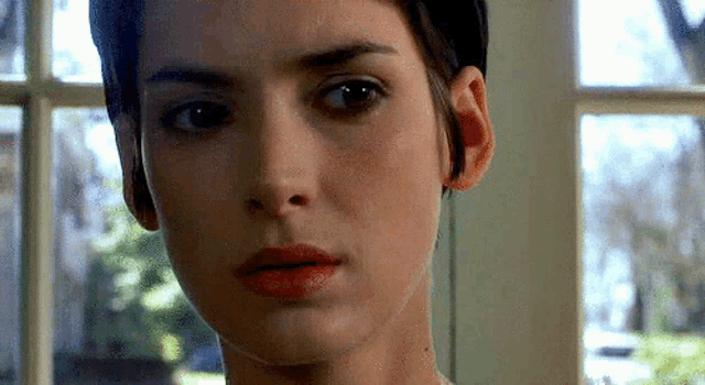 a close up of a woman 's face in front of a window