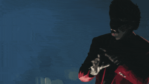 a man in a red jacket is singing into a microphone in a dark room