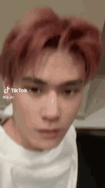 a man with red hair is wearing a white shirt and making a funny face