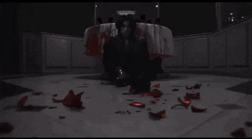 a woman is kneeling down in front of a table with blood on it
