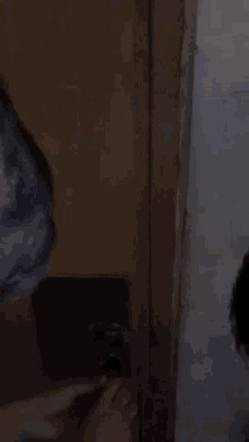 a person is standing in a bathroom next to a toilet and a door .