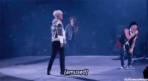 a man is standing on a stage with a microphone in his hand and saying `` amused '' .